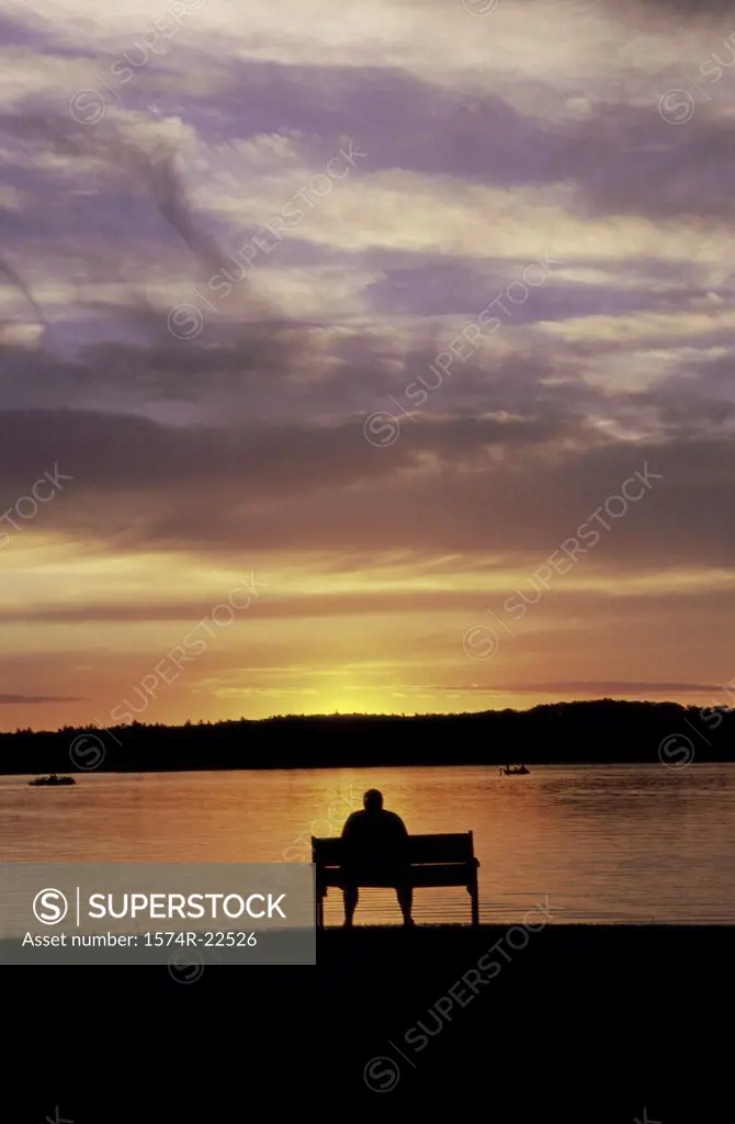 Silhouette of a person sitting on a bench during sunset