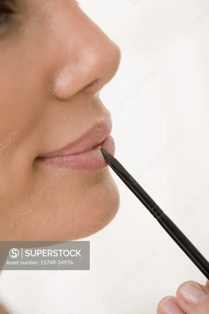 Close-up of a mid adult woman applying lipstick to her lips with a make-up brush