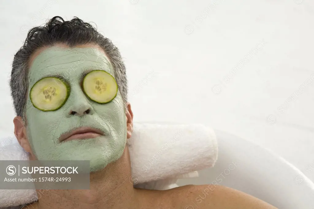 Mature man wearing a facial mask and relaxing in a bathtub