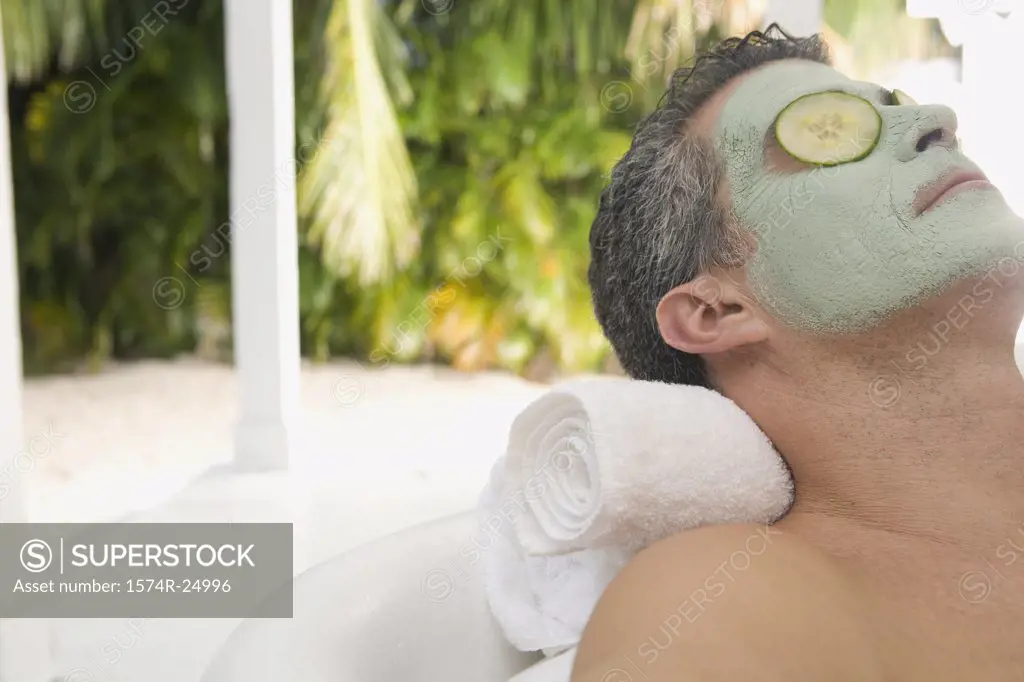 Close-up of a mature man wearing a facial mask and relaxing in a bathtub