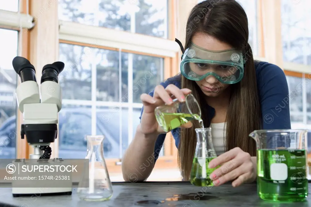Student pouring liquid in to a beaker in a science lab
