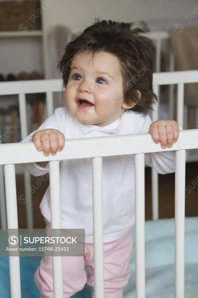 Baby girl standing in a crib