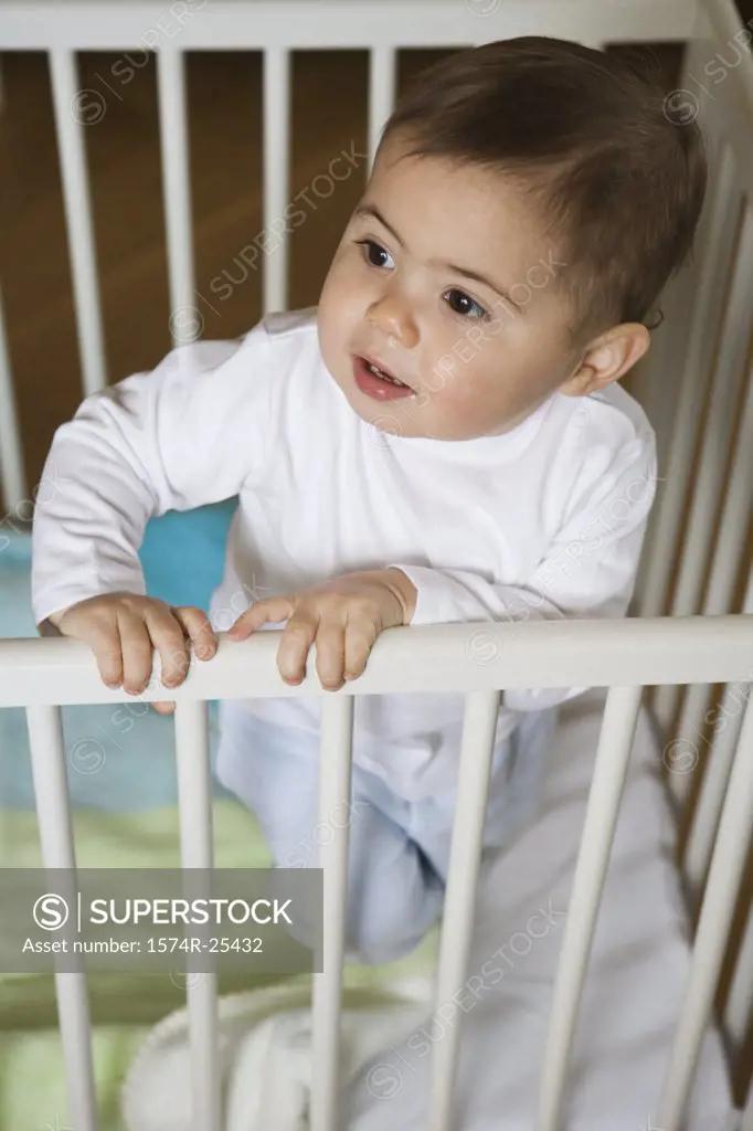 High angle view of a baby boy standing in a crib