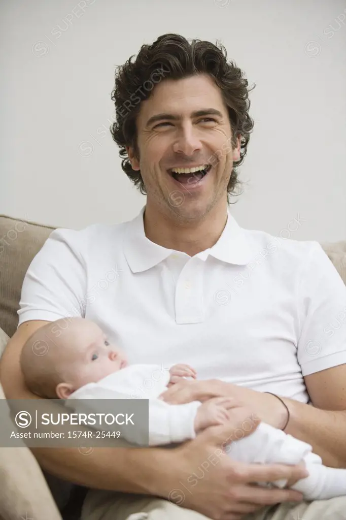 Mid adult man laughing and holding his baby