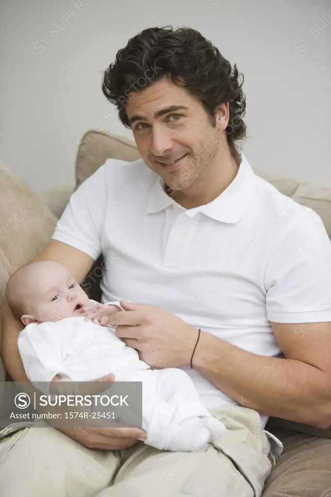 Mid adult man smiling and holding his baby