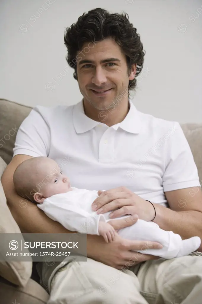 Mid adult man smiling and holding his baby