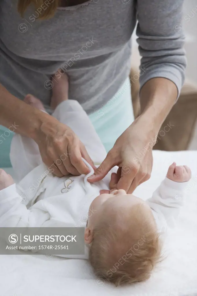 Mother putting baby clothing on her baby