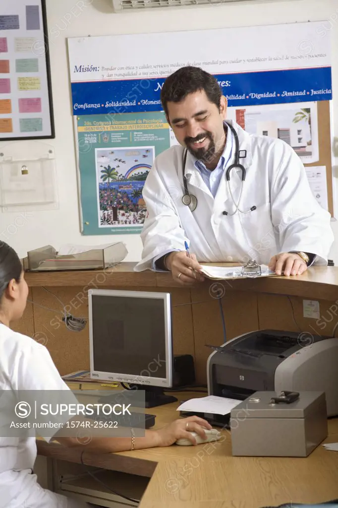 Male doctor standing at a counter and talking to a female nurse