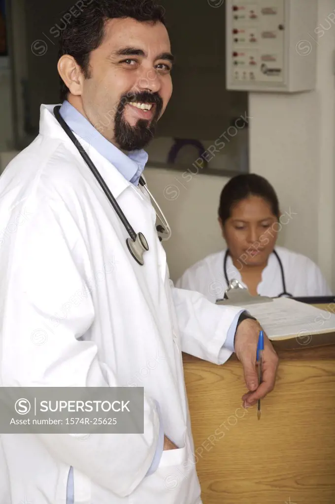 Male doctor standing at a counter and smiling