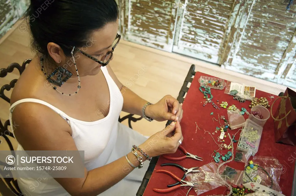 High angle view of a mature woman making jewelry in a souvenir store