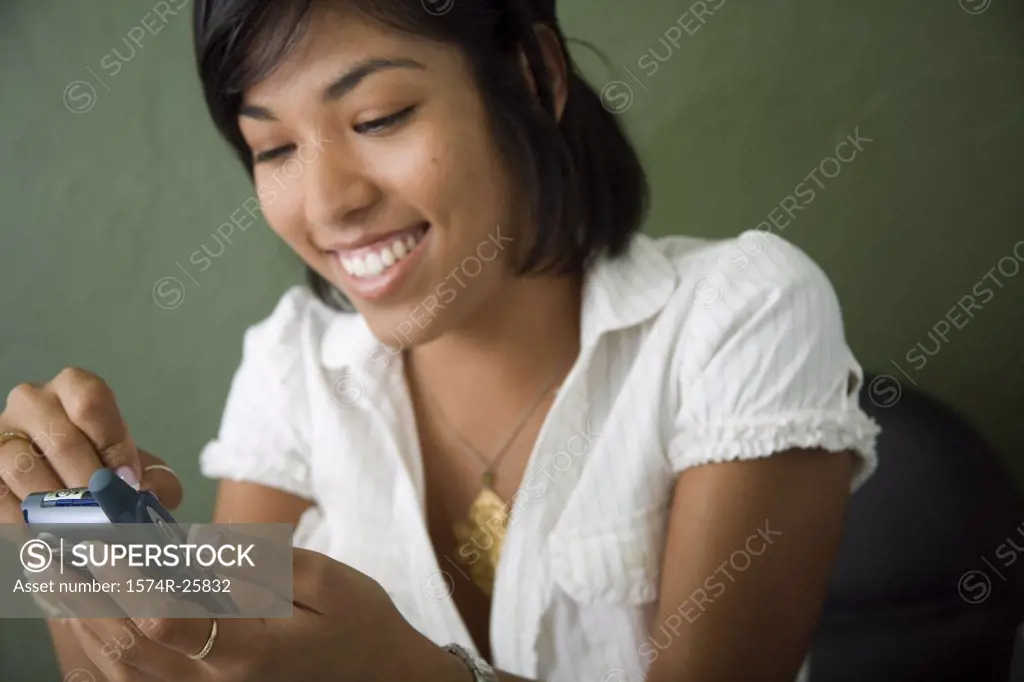 Close-up of a young woman operating a personal data assistant