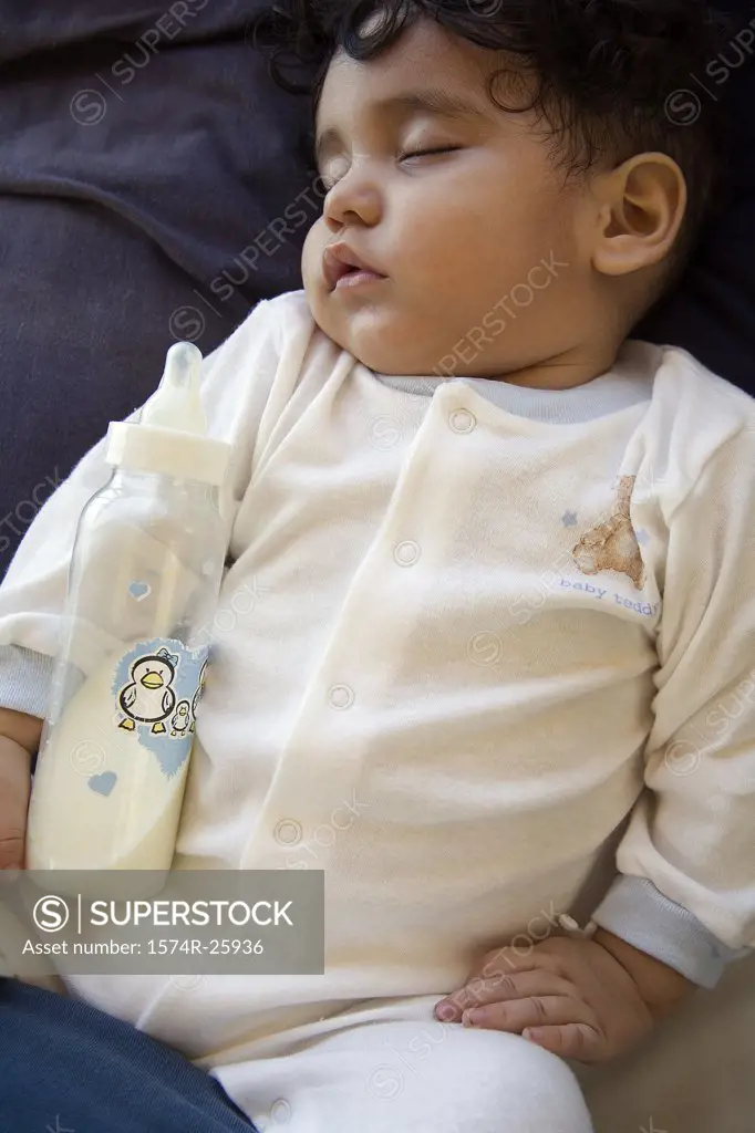 Close-up of a baby sleeping with a milk bottle