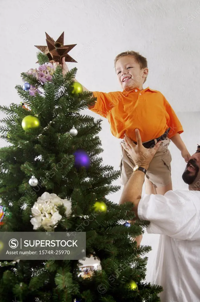 Mature man lifting his son to decorate a Christmas tree