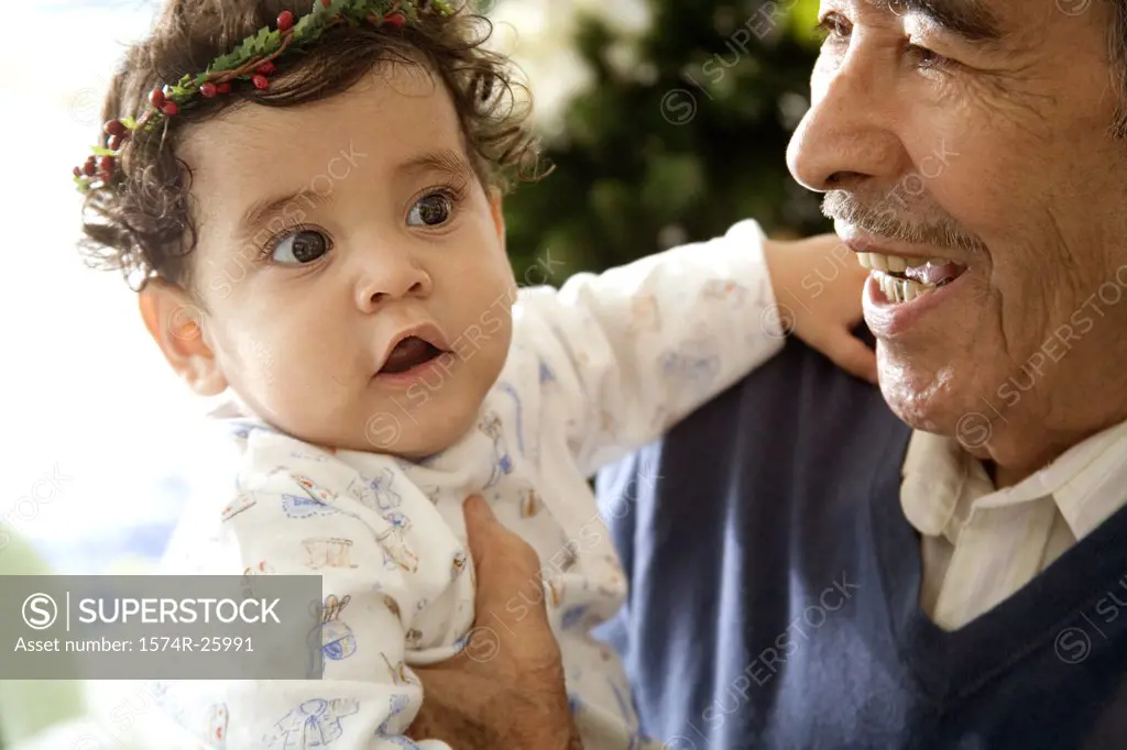 Senior man holding his great-grandchild and smiling