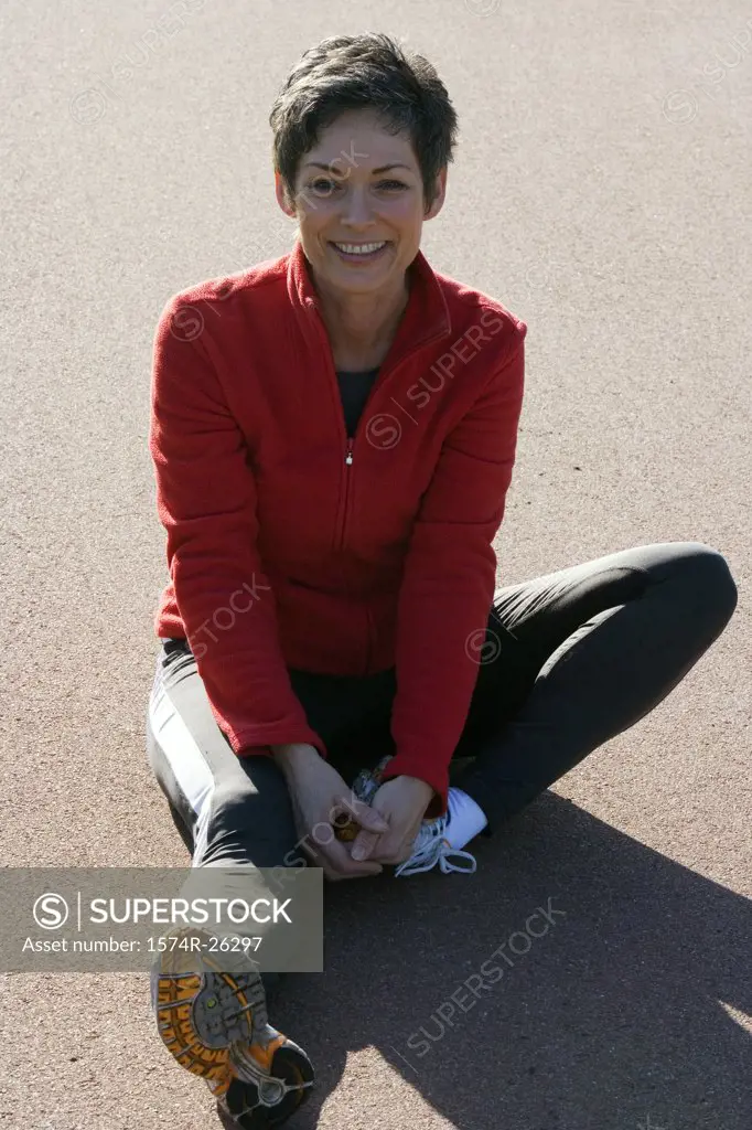 Mature woman sitting on a road and stretching
