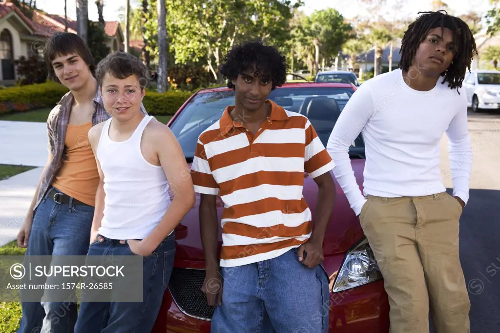 Two teenage boys and two young men leaning against a car