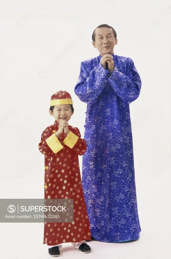 Portrait of a father and his son in traditional clothing with their hands clasped