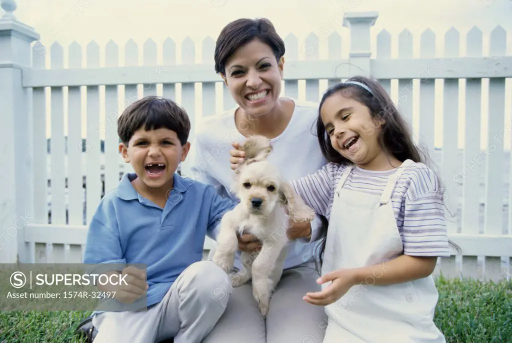 Mid adult woman holding a puppy and smiling with her son and daughter