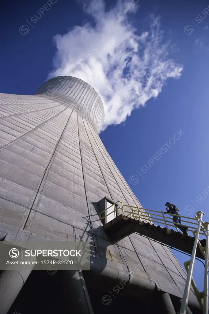 Low angle view of a person on the staircase of a smoke stack at a power plant