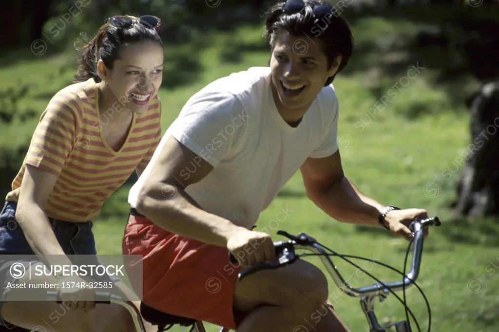 Young couple riding a tandem bicycle and smiling