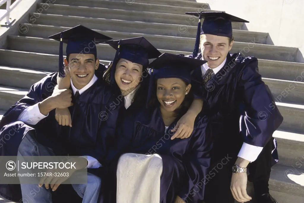 Portrait of a group of four young graduates sitting on stairs