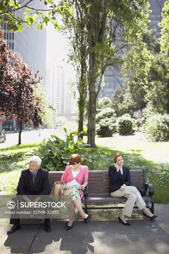 High angle view of a businessman sitting with two businesswomen on a bench