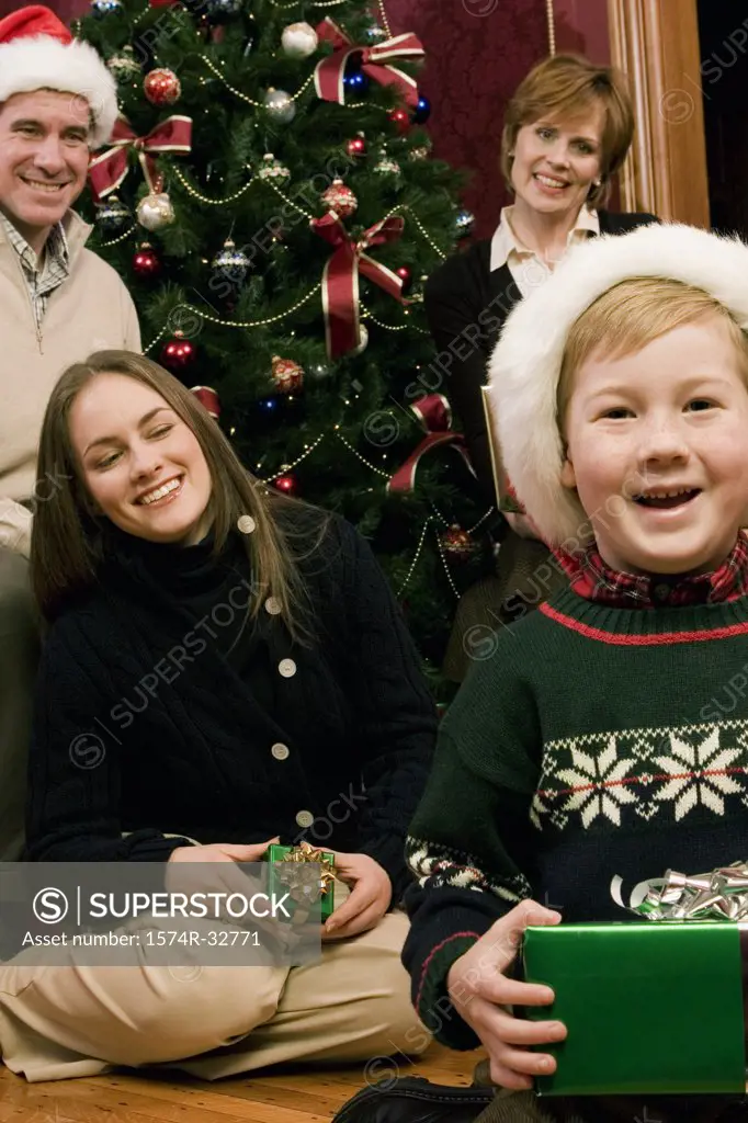 Boy holding a Christmas present with his mother and grandparents behind him