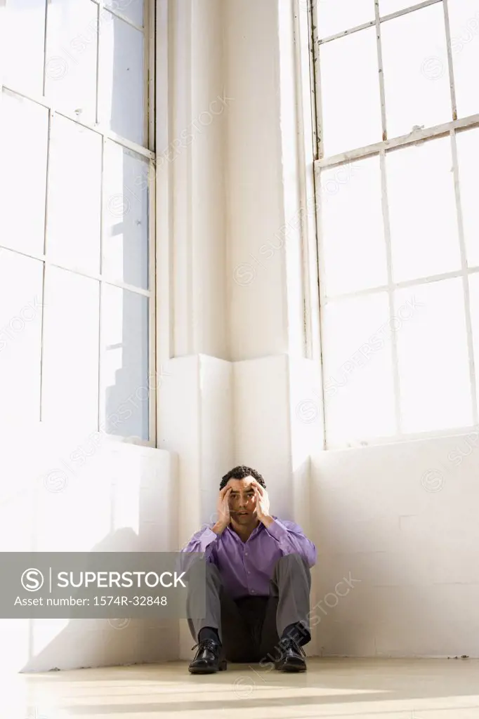 Businessman sitting on the floor in the corner of an office