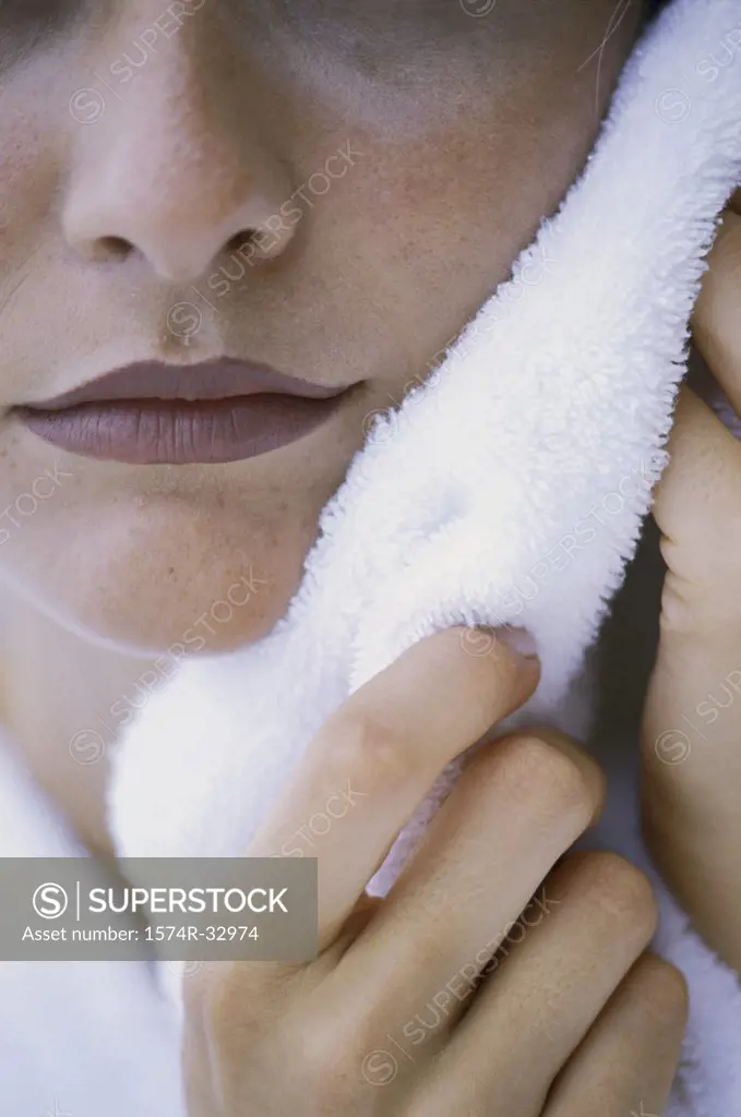 Close-up of a woman drying her face with a towel