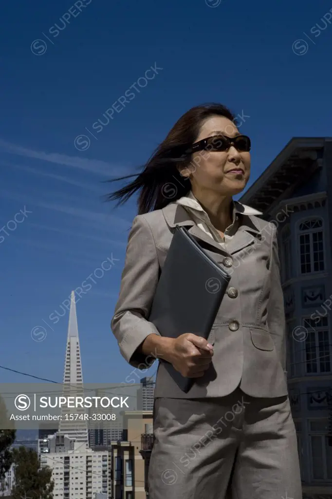 Businesswoman holding a file and smirking, San Francisco, California, USA