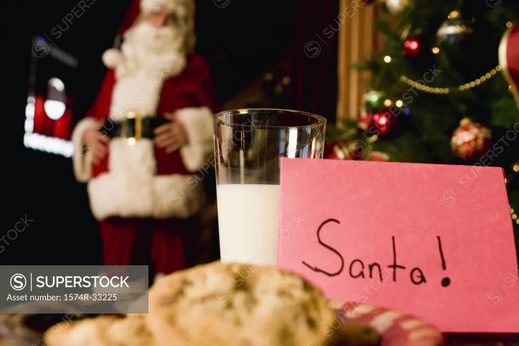 Plate of cookies and milk with Santa Claus in the background