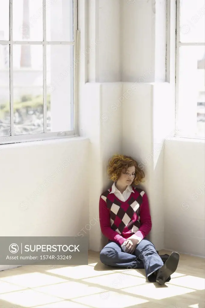 Young woman sitting on the floor in the corner of a room