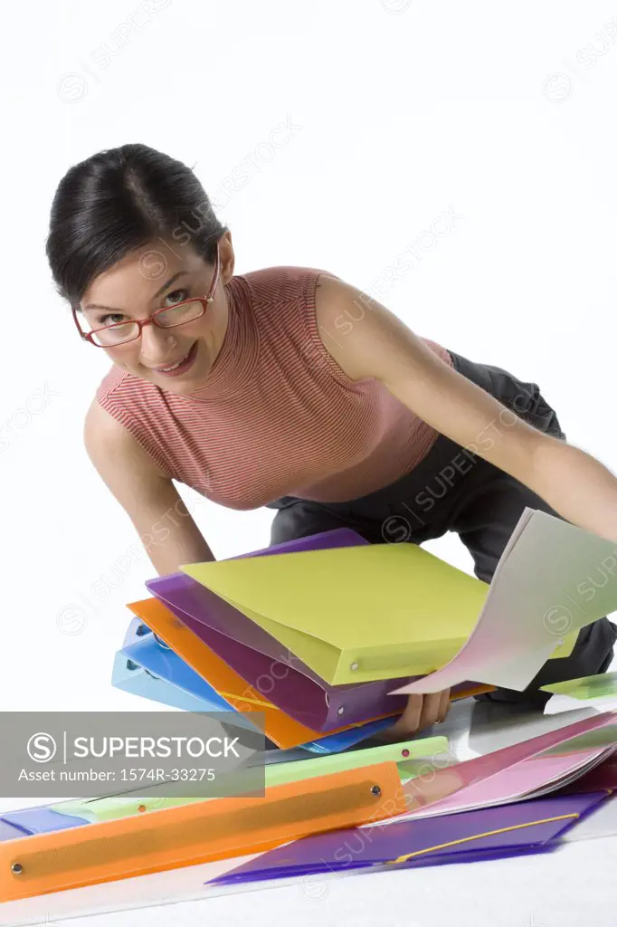 Businesswoman picking up ring binders and smiling
