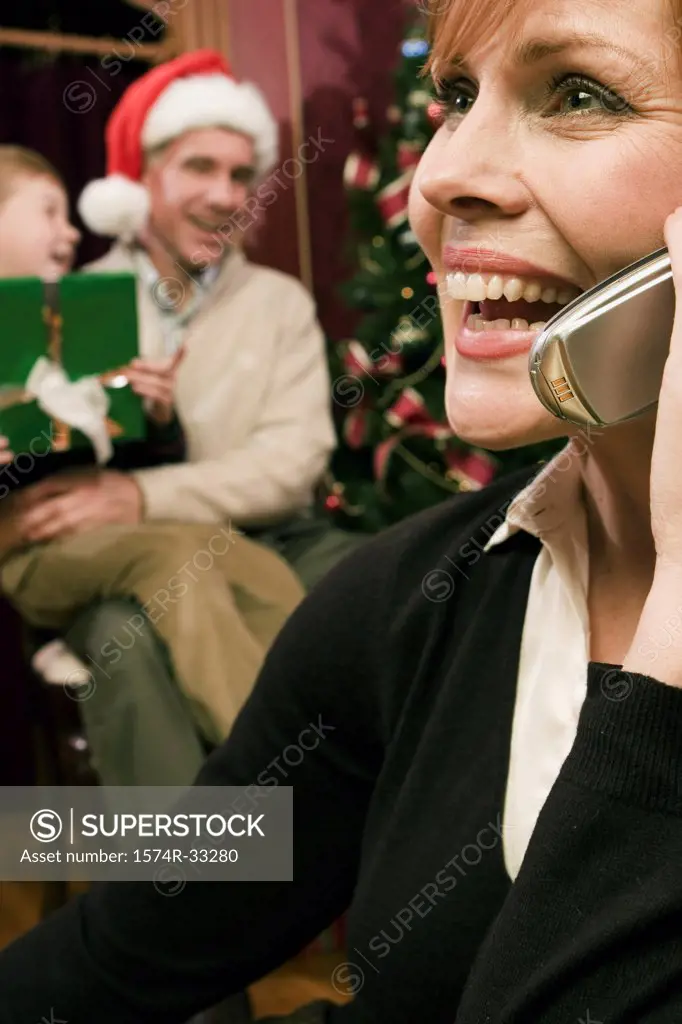 Grandfather and grandson behind a mature woman talking on a mobile phone