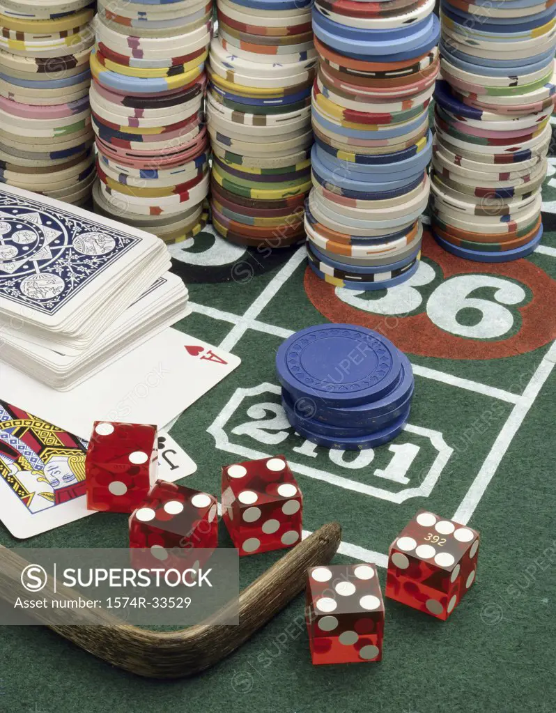 Close-up of stacks of gambling chips with playing cards and dice on a roulette table