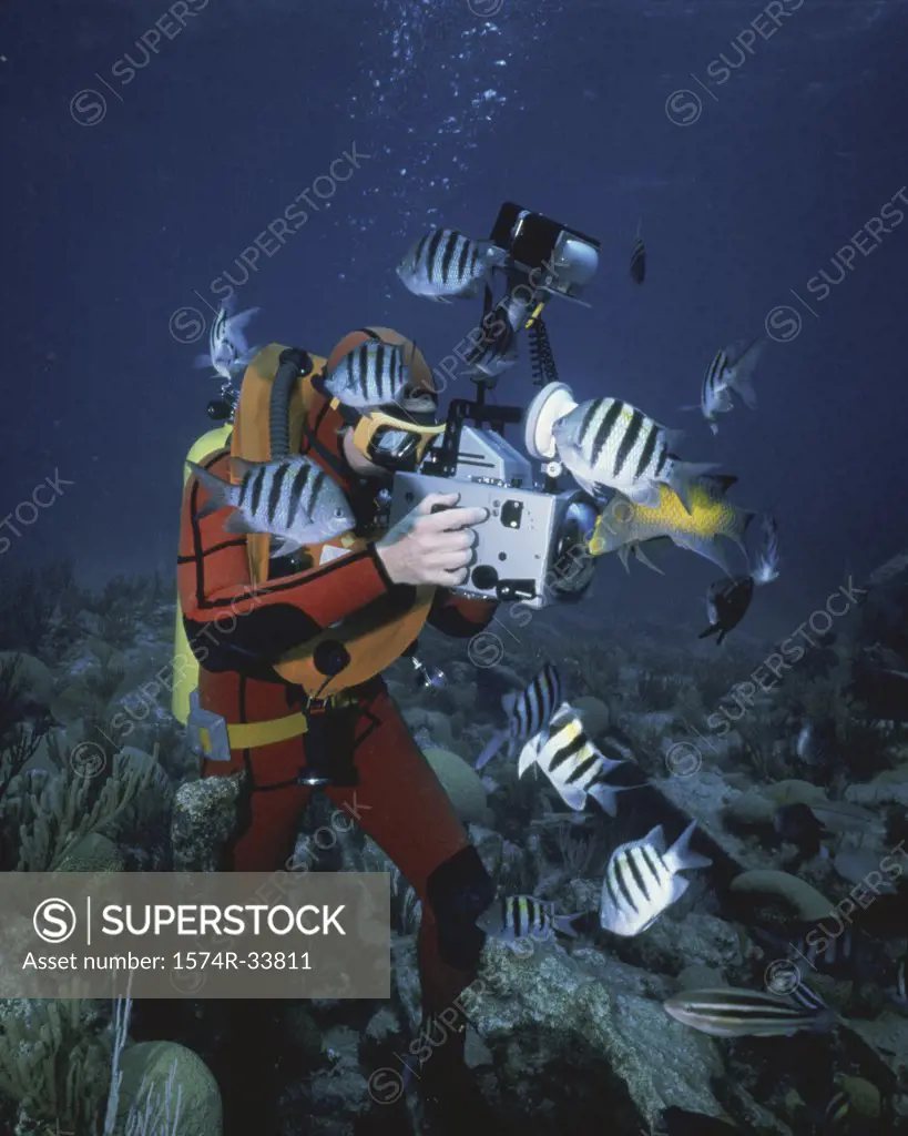 Scuba diver filming a school of fish in the sea with an underwater camera