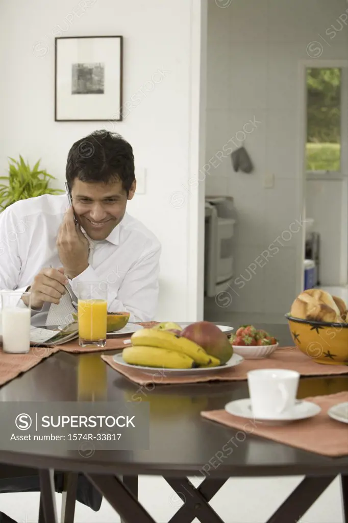 Close-up of a mature man sitting at a breakfast table and talking on a mobile phone
