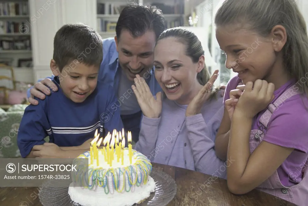 Parents with their son and daughter in front of a birthday cake