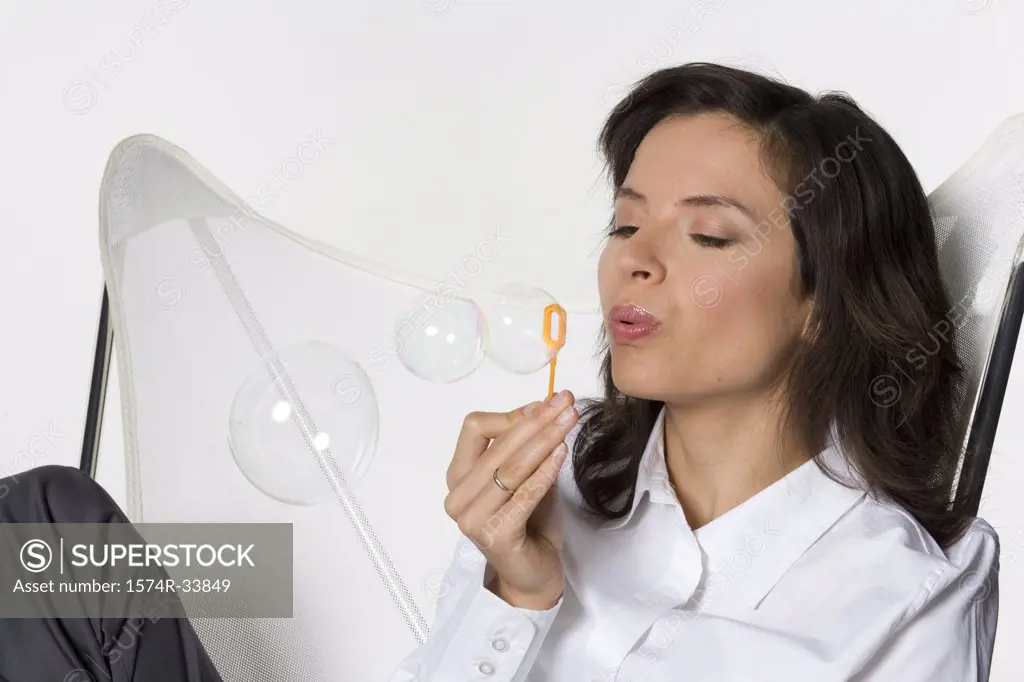 Close-up of a young woman blowing bubbles with a bubble wand