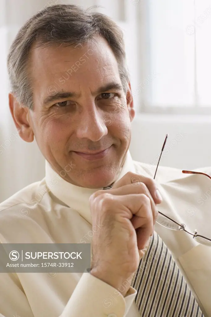 Close-up of a businessman holding eyeglasses and smiling
