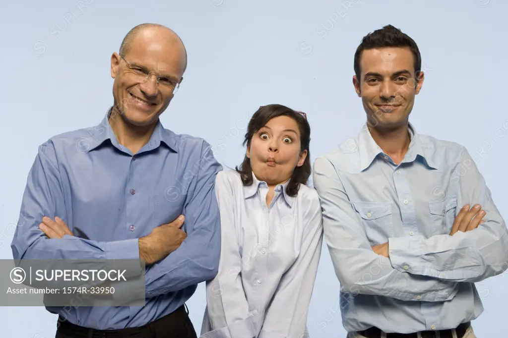 Two businessmen standing with their arms crossed and a businesswoman making a face between them