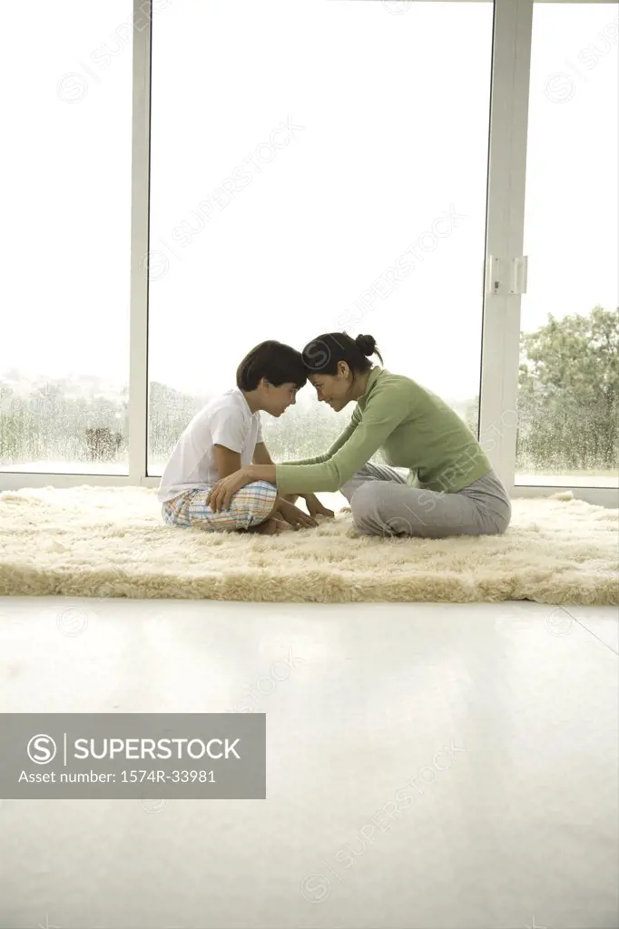 Side profile of a young woman playing with her son on a rug