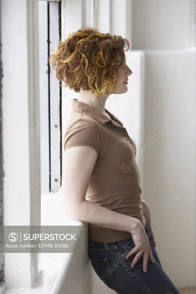 Side profile of a young woman leaning against a window