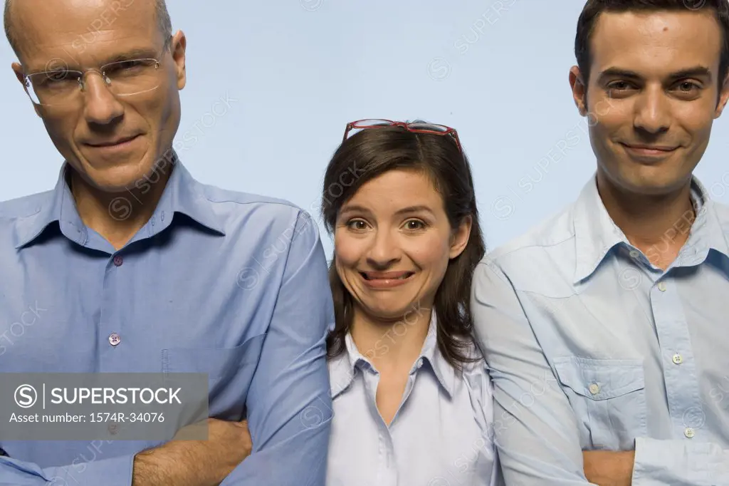 Portrait of two businessmen smiling with a businesswoman making a face between them