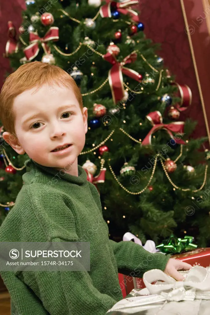 Portrait of a boy in front of a Christmas tree with Christmas presents