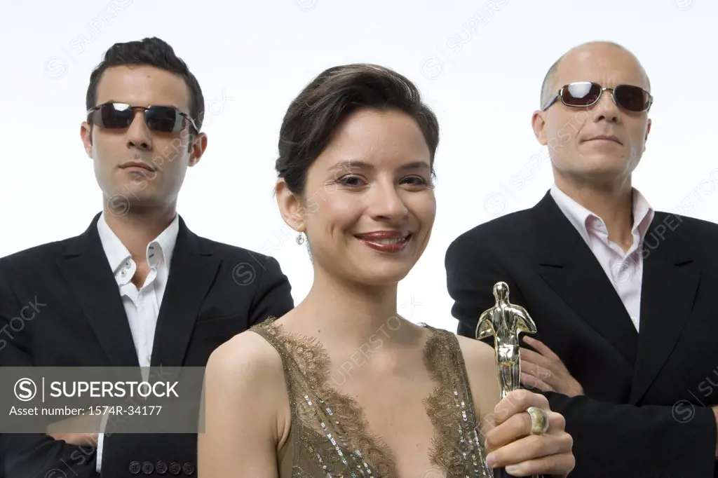 Portrait of a young woman holding a trophy with a young man and a mature man standing behind her