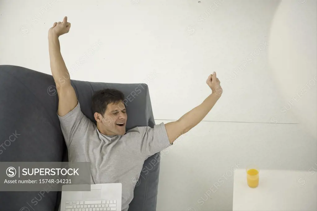 High angle view of a mature man lying on a couch and stretching his arms