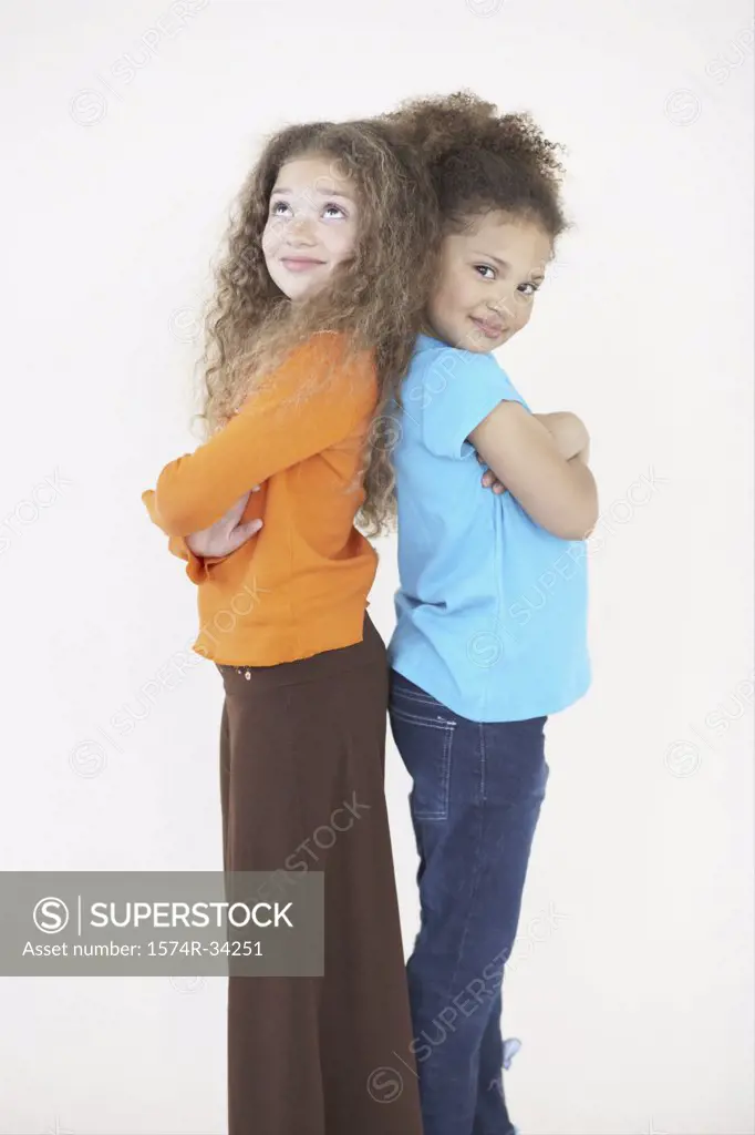 Side profile of two girls standing back to back with their arms crossed