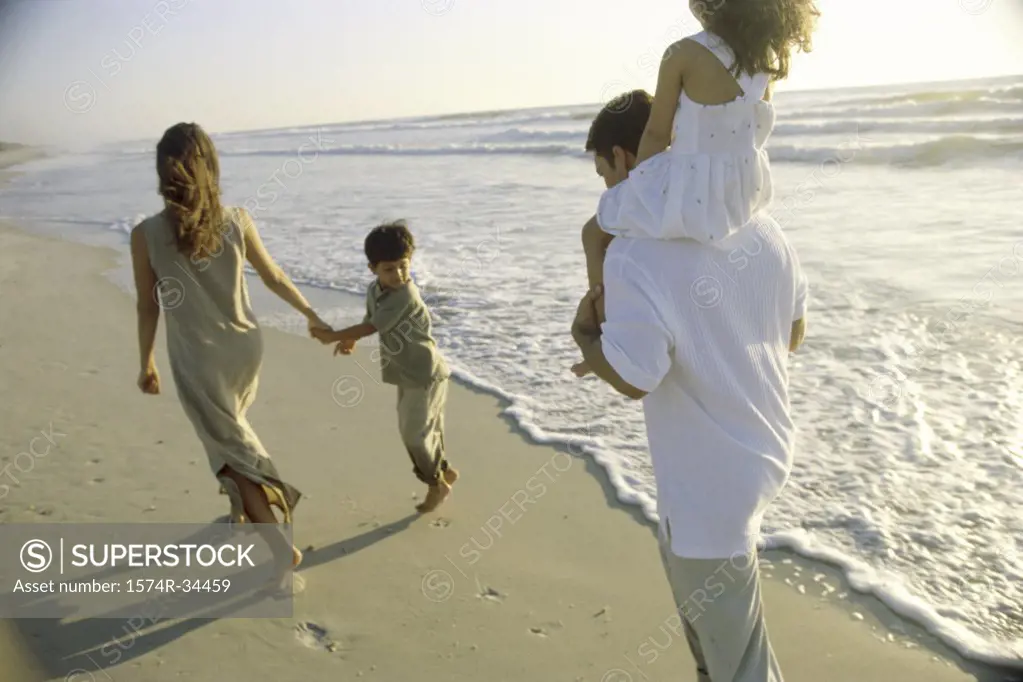 Young couple walking on the beach with their son and daughter