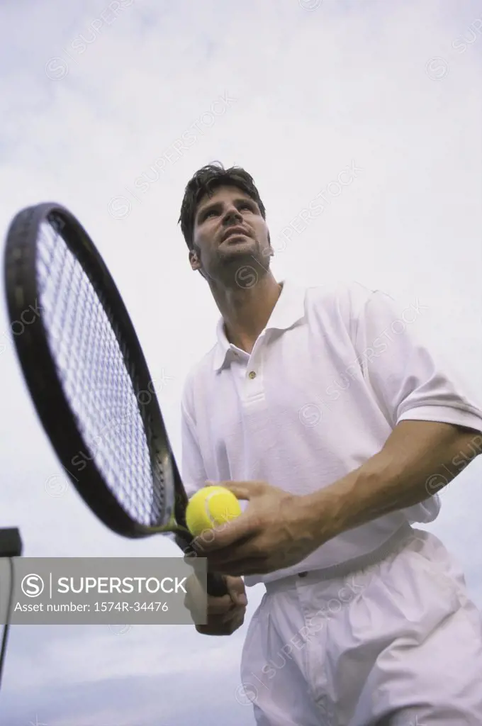 Low angle view of man holding a tennis ball and a tennis racket